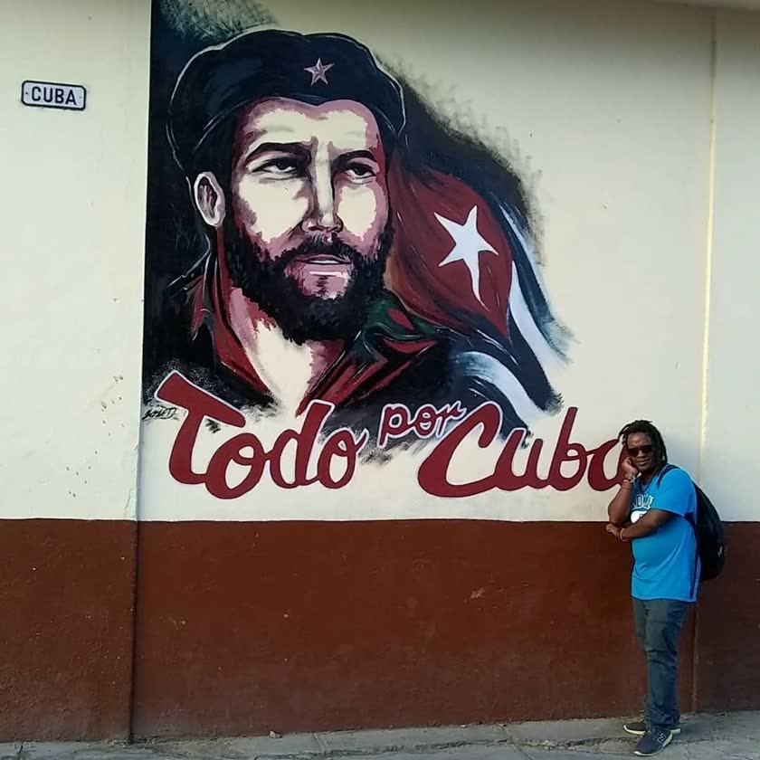 Yoyo leaning in front of the ‘Todo por Cuba’ mural of Che Guevara, 2019